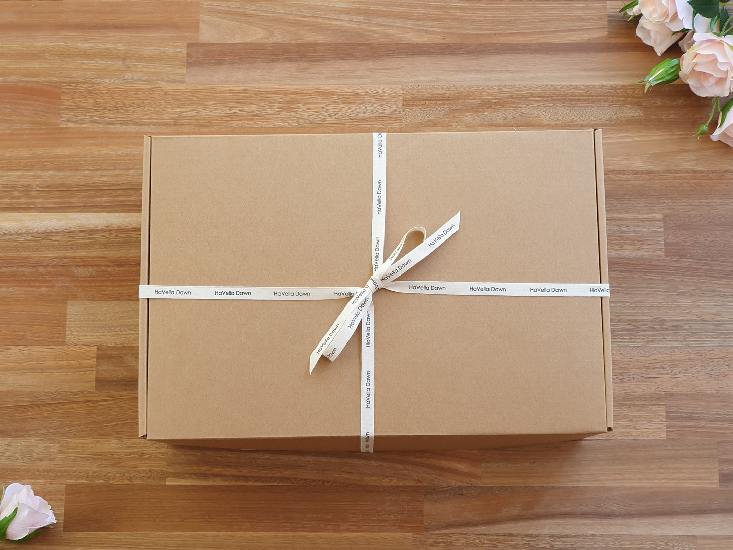 Brown gift box with white ribbon on a wooden surface