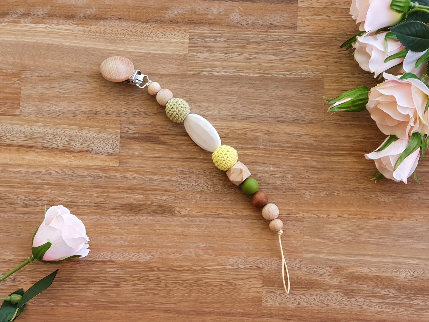 A beaded baby pacifier chain with a natural wood clip, textured green, and yellow beads.