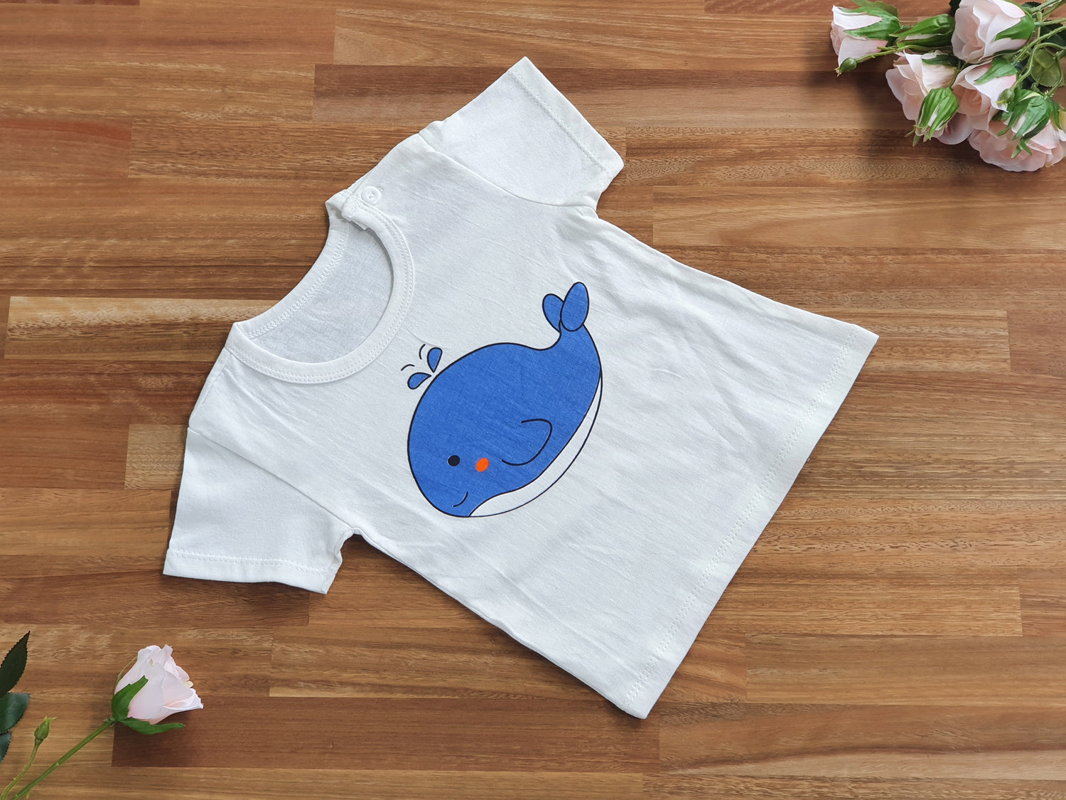 A white short-sleeve baby t-shirt with a blue whale graphic