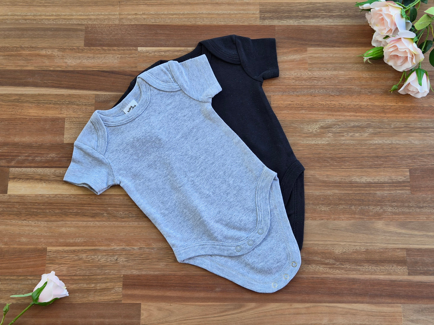 Two short-sleeve baby rompers: one light grey and one black.